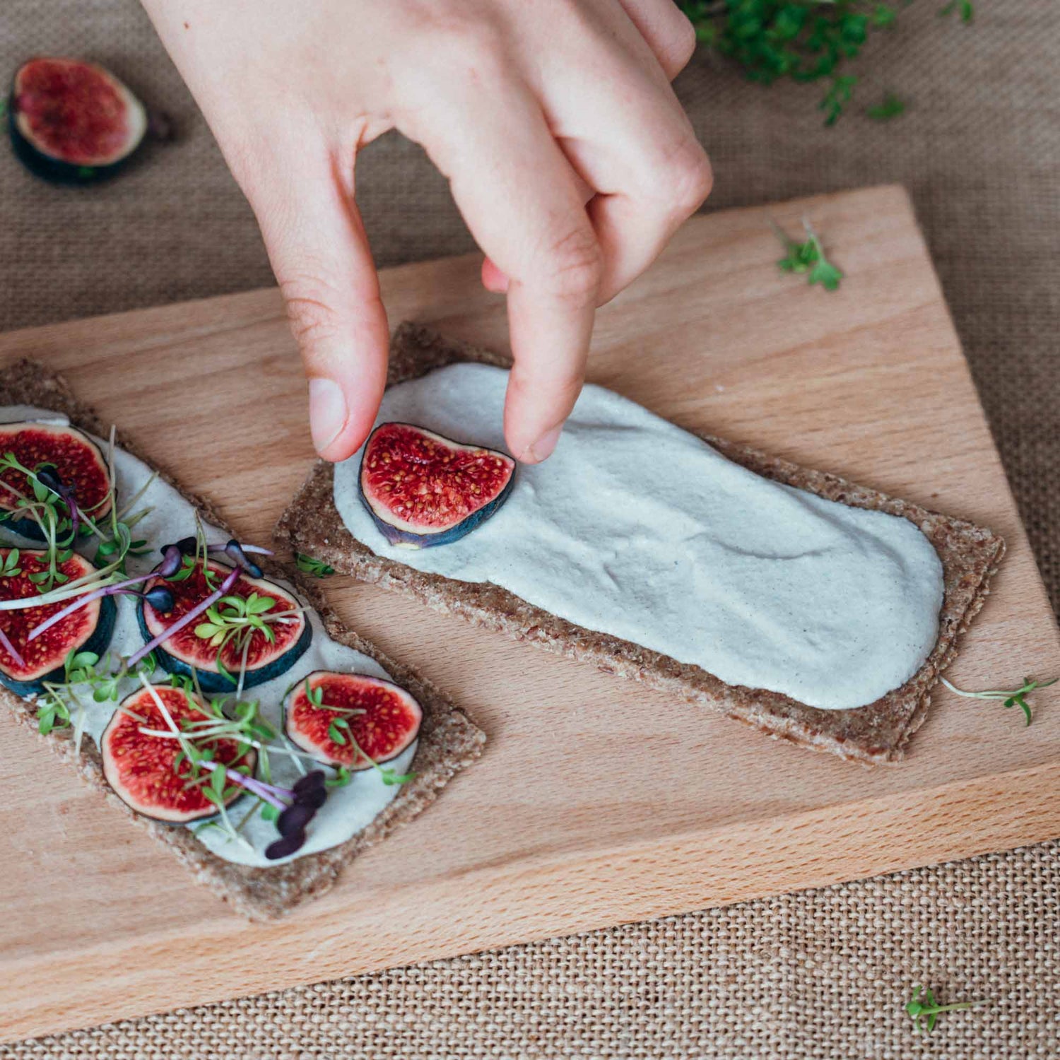 Eine Hand belegt ein Essener Rohkostbrot mit Feigen